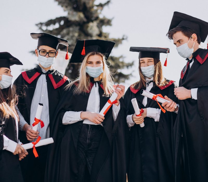 Group of students celebrating graduation together and wearing face masks